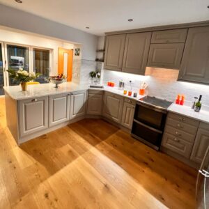 Open plan kitchen, light grey units with white grain, quartz worktop.