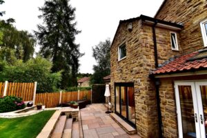 Domestic random stone single storey rear extension with Indian stone landscaping.